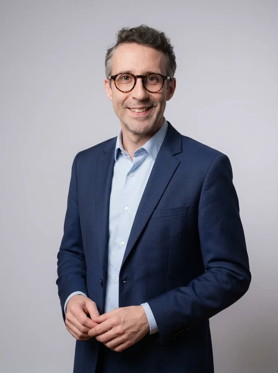Portrait IA dentiste style corporate classique — variante costume bleu marine sans cravate, chemise bleu clair ouverte, fond studio neutre