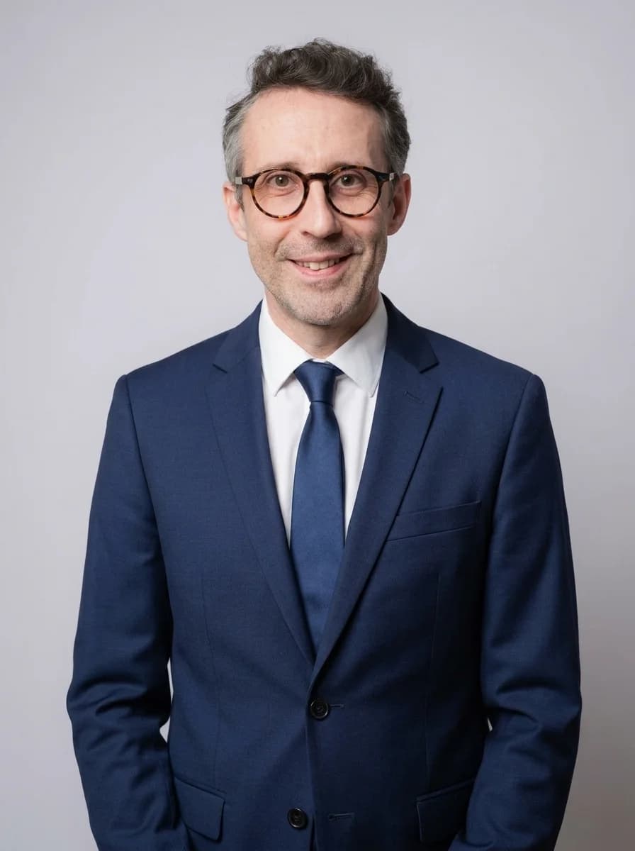 Portrait IA dentiste style corporate classique — costume bleu marine, cravate bleue, chemise blanche, fond studio neutre, cadrage poitrine pour Doctolib