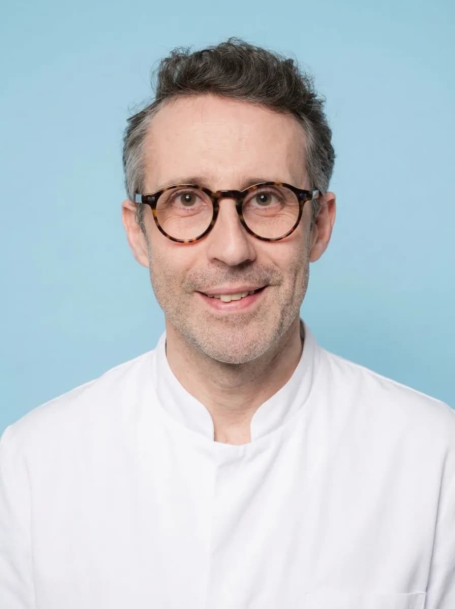 Exemple de portrait dentiste en blouse médicale blanche sur fond bleu clinique - chirurgie et implantologie